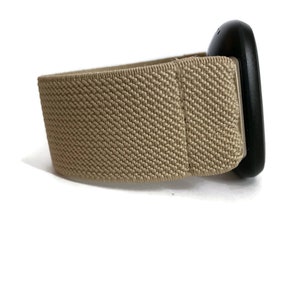 K&ouml;nnte beinhalten: Ein beigefarbenes elastisches Armband mit einer schwarzen Schnalle.