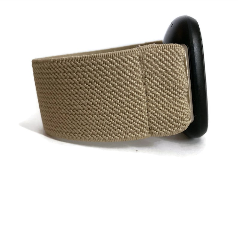 K&ouml;nnte beinhalten: Ein beigefarbenes elastisches Armband mit einer schwarzen Schnalle.