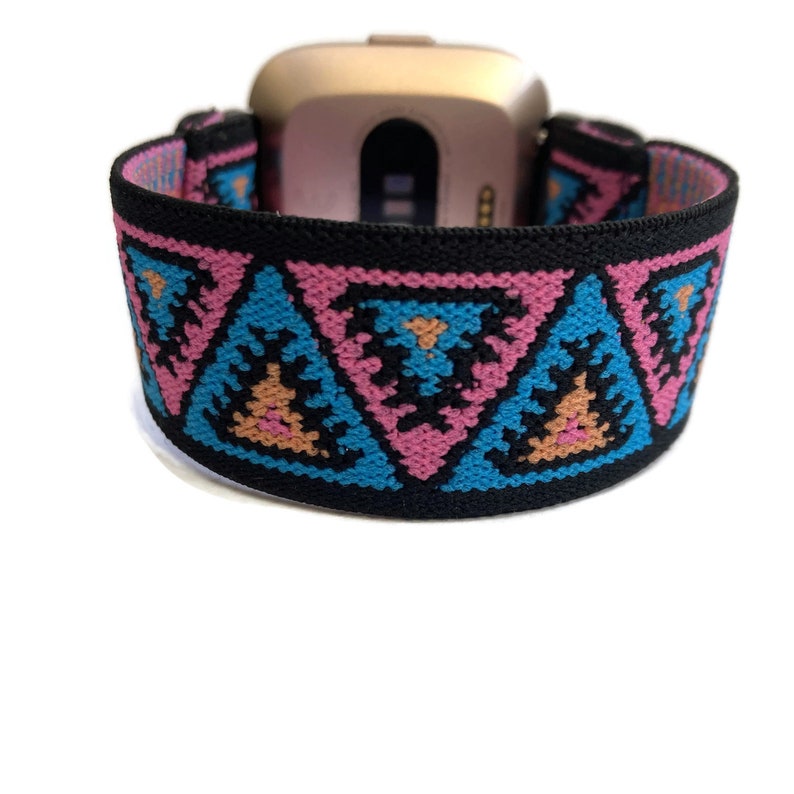 May include: A black elastic watch band with a geometric pattern of pink, blue, and orange triangles. The band is designed to fit a smartwatch.