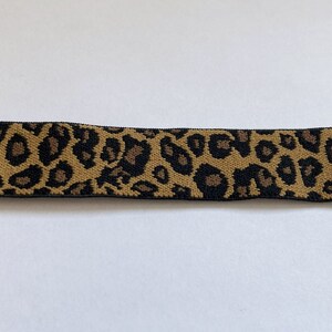 May include: A brown and black leopard print elastic belt with gold metal ends.