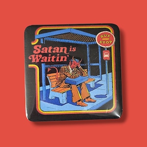 May include: A square pin featuring a graphic illustration of a red devil with horns and a tail sitting on a bench at a bus stop. The devil wears a brown suit and holds a blue briefcase. The text reads "Satan is Waitin'" and "BUS STOP".