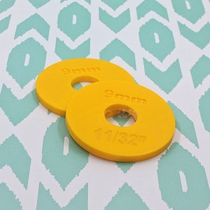 Puede incluir: Dos anillos de tamaño de gancho de ganchillo de plástico amarillo, uno etiquetado "9 mm" y el otro etiquetado "9 mm 11/32"