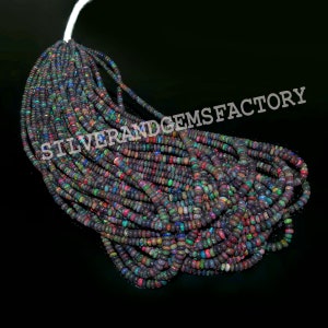 May include: Strands of black opal beads with flashes of color, including red, blue, and green. The beads are small and round, strung together on a white cord. The text "SILVERANDGEMSFACTORY" is visible.