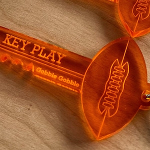 May include: Orange plastic key chain shaped like a football with the words "KEY PLAY" and "Gobble Gobble" on it.