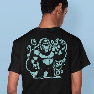 Könnte beinhalten: Schwarzes T-Shirt mit einer blauen Grafik eines Gorillas, der die Faust hebt.