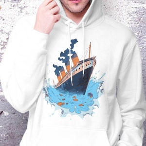Peut inclure: Sweat-shirt à capuche blanc avec un imprimé graphique d'un navire qui coule avec de la fumée sortant des cheminées. Le navire est entouré d'eau bleue avec des éclaboussures blanches.