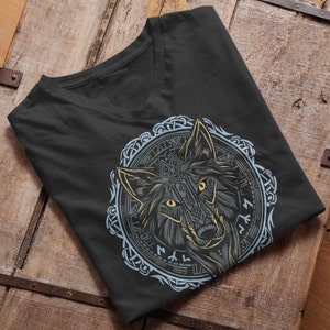 Könnte beinhalten: Ein schwarzes V-Ausschnitt-T-Shirt mit einem Motiv eines Wolfskopfes in einem Kreisdesign. Der Wolfskopf ist mit komplizierten Mustern verziert und der Kreis ist mit einem Knotenmuster verziert.
