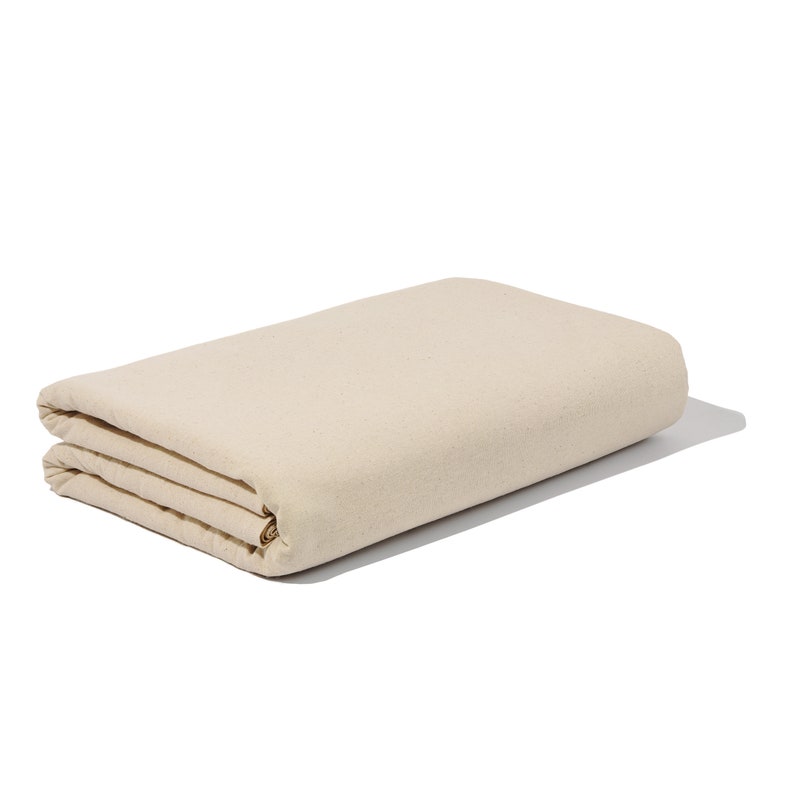 May include: A folded, off-white canvas drop cloth. The cloth is folded in thirds and has a subtle texture.
