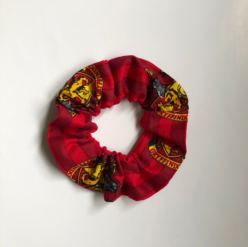 May include: Red and yellow hair scrunchie with the Gryffindor house crest and the words "Gryffindor" repeated around the crest.