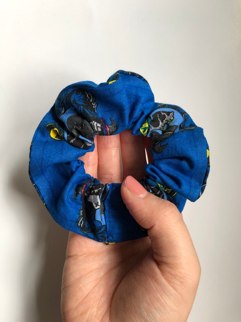 May include: Blue fabric scrunchie with a black and yellow print of a cartoon character.