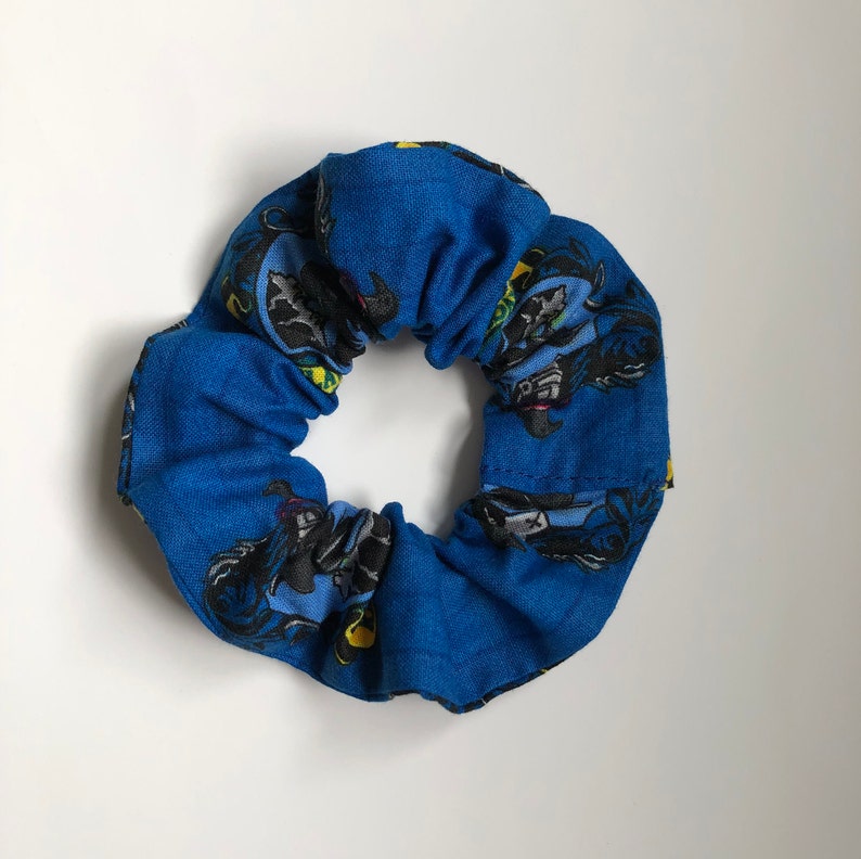 May include: A blue fabric scrunchie with a repeated pattern of a cartoon character riding a motorcycle.