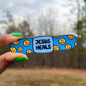 May include: Blue and yellow band-aid sticker with the text "JESUS HEALS" and a pattern of smiley faces.