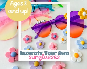 May include: A set of colorful sunglasses with a gradient lens. The sunglasses are decorated with colorful flower stickers. The text "Ages 8 and up!" and "Decorate Your Own Sunglasses" is on the image.