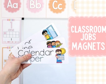 May include: A hand holding classroom job magnets with illustrations of children and the words "Line", "Calendar", and "Paper". The image also shows a pink sign that says "Classroom Jobs Magnets" and alphabet and number charts.