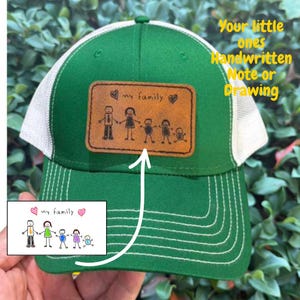 May include: Green and white trucker hat with a leather patch featuring a family stick figure drawing and the words "my family." The hat has a curved brim and mesh back. Text on the hat says "Your little ones Handwritten Note or Drawing."
