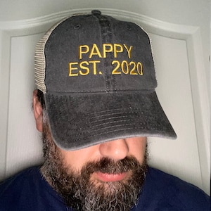May include: A black and gray mesh trucker hat with the text "PAPPY EST. 2020" embroidered in yellow.