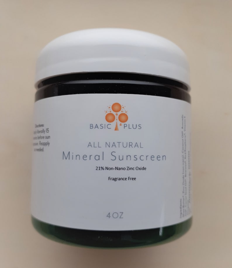 K&ouml;nnte beinhalten: Ein wei&szlig;es Glas mit gr&uuml;nem Deckel, beschriftet mit "BASIC PLUS ALL NATURAL Mineral Sunscreen 21% Non-Nano Zinc Oxide Fragrance Free 4 OZ"