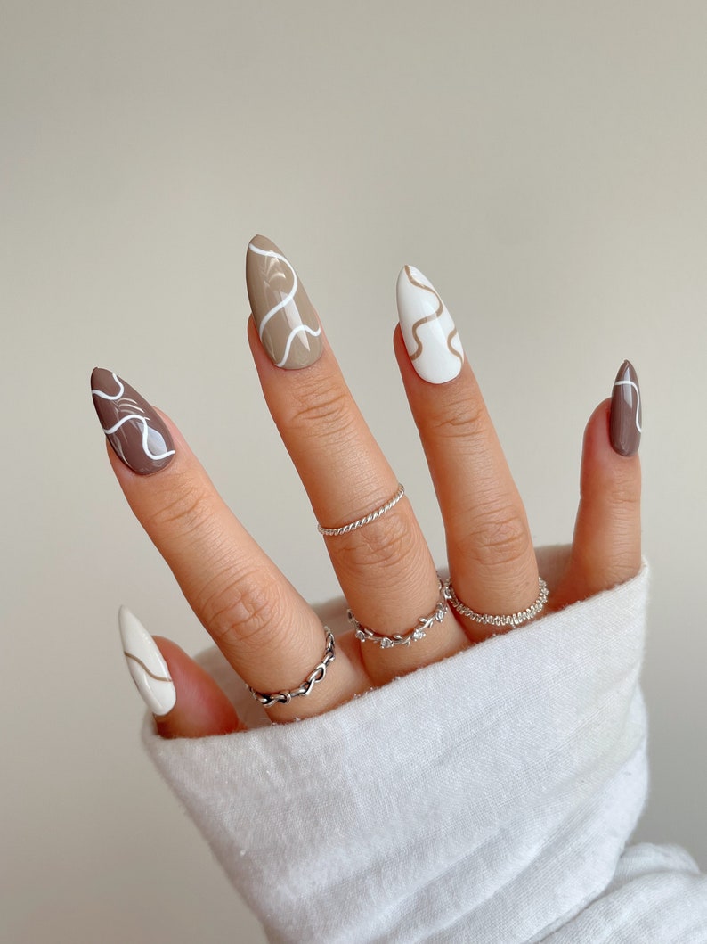 May include: Almond shaped nails with a white base and brown swirls, and a brown base with white swirls.
