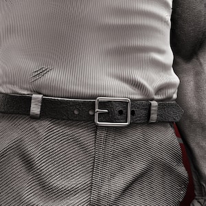 May include: A close-up of a person wearing a gray ribbed shirt with a black leather belt and a silver buckle. The shirt has several small tears.