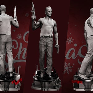 May include: A gray figurine of a man holding a gun in each hand. The figurine is standing on a black base with a red ribbon. The background is red with snowflakes.