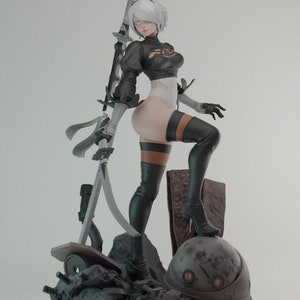 Op de afbeelding: Een vrouwelijke action figure met wit haar, gekleed in een zwart-witte outfit, die een zwaard vasthoudt. De figuur staat op een basis met een metalen bol en ander puin.