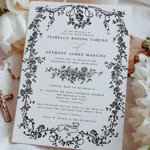 May include: A wedding invitation with black floral border and text. The invitation includes the names Isabella Rosina Caruso and Anthony James Mancini, and details for the nuptial mass. A lit candle, white flowers, and a rosary are in the background.