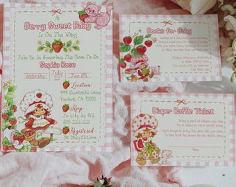 May include: A baby shower invitation set with a strawberry theme. The set includes an invitation, a book request card, and a diaper raffle ticket. The invitation features the text "Berry Sweet Baby" and the name "Sophia Rose". Fresh strawberries and a lit candle are also present.