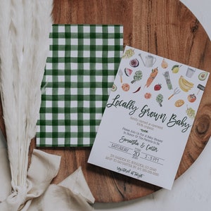May include: A white card with green and white checkered paper behind it. The card is a baby shower invitation with the text "Locally Grown Baby" and the text "Please join us for a baby shower in honor of the parents to be Samantha & Carter" and the date "Saturday, March 20, 2020, 2-5 PM". The card is decorated with a watercolor illustration of various fruits and vegetables.