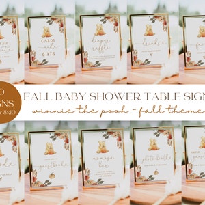 May include: Ten printable baby shower table signs featuring a Winnie the Pooh theme with fall colors and a bear illustration. The signs include titles such as "Babies are Sweet", "Cards and Gifts", "Diaper Raffle", "Drinks", "Favors", "Food", "Guestbook", "Mimosas Bar", "Photo Booth", and "Photo Guestbook".