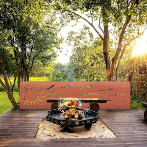 May include: A backyard scene featuring a burning fire pit with a decorative metal screen. The fire pit is black, hexagonal, and filled with burning logs. The screen is rust-colored with a sunburst design. The scene is set on a wooden deck.