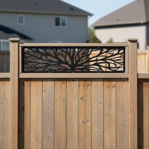 May include: A wooden fence featuring a black metal tree design. The tree design is centrally placed and framed by a light-coloured wooden border. The fence is constructed from vertical wooden planks.