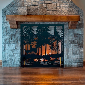 Peut inclure: Un écran de cheminée en métal noir représentant une scène de forêt avec des arbres, des cerfs et une silhouette d'aigle. L'écran est placé devant une cheminée en pierre avec un manteau en bois. Le feu brille chaleureusement derrière l'écran.