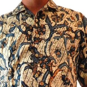 Könnte beinhalten: Kurzärmeliges Button-Down-Hemd mit Batik-Blumenmuster in Braun, Blau und Creme auf cremefarbenem Hintergrund. Das Hemd hat einen klassischen Kragen und eine Knopfleiste.