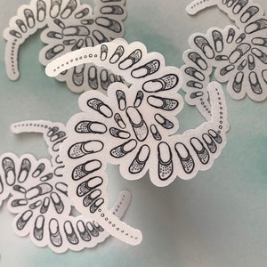 May include: Five white stickers with black outlines of a spiral pattern of pills. The stickers are arranged in a cluster on a light blue background.
