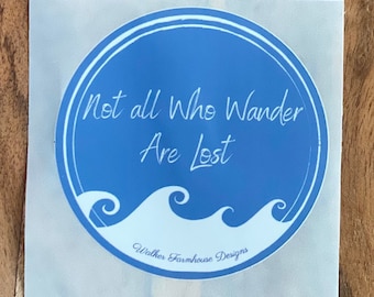 Könnte beinhalten: Ein runder Aufkleber mit blauem Hintergrund und weißem Text, der lautet: "Not all Who Wander Are Lost". Der Aufkleber hat einen weißen Rand und ein Wellendesign. Der Text "Walker Farmhouse Designs" befindet sich unten.