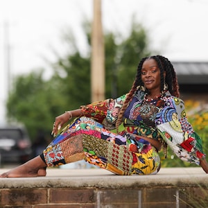 May include: A two-piece outfit consisting of a long-sleeved cropped top and matching pants, both featuring a vibrant, multi-colored patchwork design with various geometric and floral patterns in shades of yellow, red, blue, green, and black.
