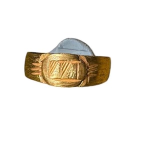 Op de afbeelding: Een gouden ring met een geometrisch ontwerp aan de bovenkant. De ring is breed en heeft een platte band.