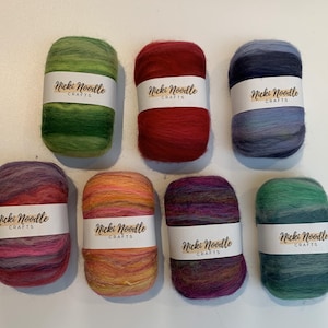 Puede incluir: Ocho ovillos de lana teñida a mano en varios colores, incluyendo verde, rojo, azul, morado, naranja y azul verdoso. Cada ovillo tiene una etiqueta que dice "Nicki Noodle Crafts".