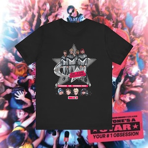 以下が含まれることがあります： 黒いTシャツ。銀と白の衣装を着たボーイバンドのグラフィックが星を背景に描かれています。「UR FAV BOYBAND」と「CHOOSE UR CHARACTER」の文字も表示されています。背景には大勢の人々がいます。