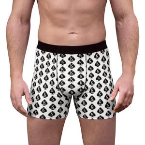 Könnte beinhalten: Boxershorts mit einem sich wiederholenden Muster aus schwarzen Pik-Symbolen, die jeweils einen weißen Buchstaben K in der Mitte enthalten. Das Kleidungsstück hat einen einfarbigen schwarzen Gummibund und eine weiße Grundfarbe.