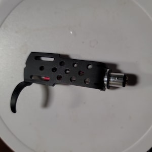 May include: Black plastic record player tonearm with a silver connector and gold-colored pins.