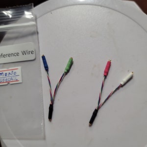 May include: Close-up of several reference wires with colored connectors. The wires have blue, green, red, and white connectors. The wires are multi-colored and appear to be for audio or electronic devices. A label reads "Reference Wire".