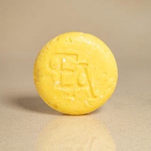 May include: A yellow round bar of soap with the letter "B" embossed on the top.