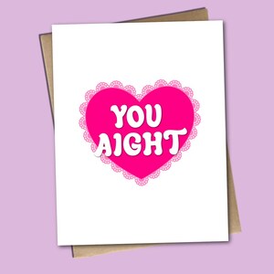 May include: A pink heart with a white lace border and the text "YOU AIGHT" in white letters.