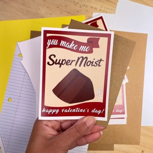 May include: A red and white card with the text "you make me Super Moist" and a brown chocolate cake illustration. The card also says "happy valentine's day!"