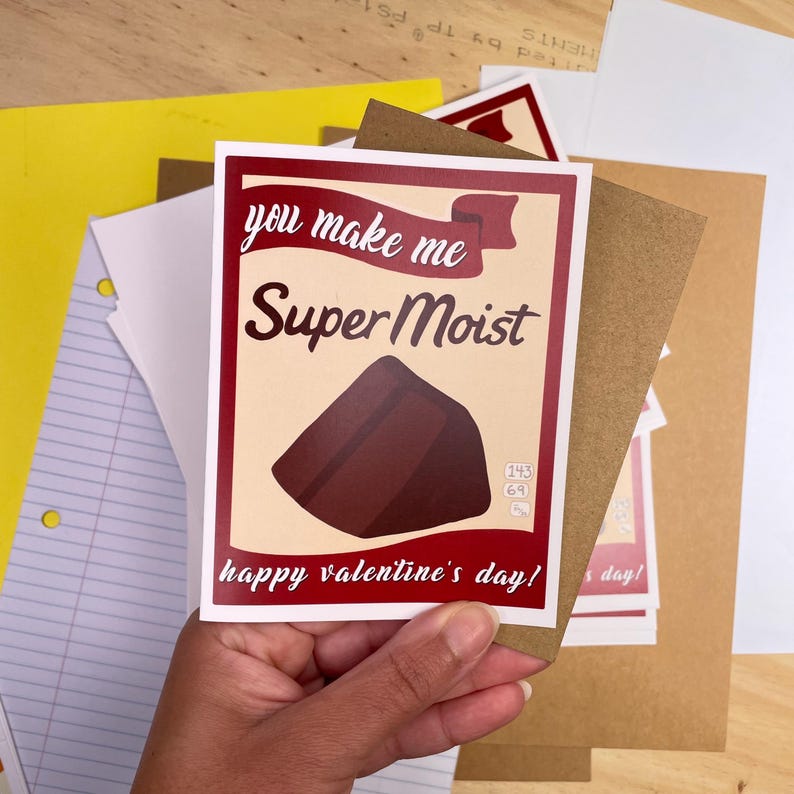 May include: A red and white card with the text "you make me Super Moist" and a brown chocolate cake illustration. The card also says "happy valentine's day!"