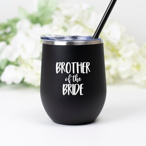 May include: Black stainless steel wine tumbler with a white inscription that reads "Brother of the Bride".