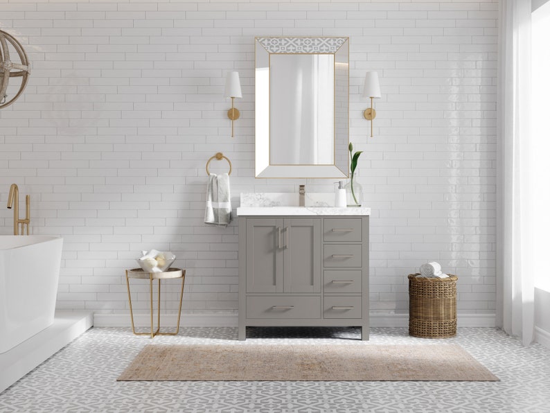 May include: A grey bathroom vanity with two doors and three drawers. The vanity has a white countertop and a gold tap. The vanity is in front of a white tiled wall with a gold mirror above it.