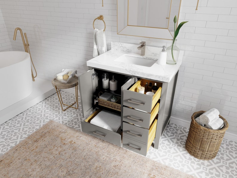 May include: A grey bathroom vanity with a white countertop and a white porcelain sink. The vanity has four drawers and a cabinet door. The drawers are open, revealing wooden drawer boxes. The vanity is in a bathroom with white subway tile walls and a patterned floor.