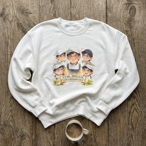May include: White crew neck sweatshirt with a cartoon illustration of five chefs wearing glasses and hats. The graphic includes the text "IT'S ME... PERILLA OIL CHEF CHOI KANG ROK". A small bottle of oil is also depicted.